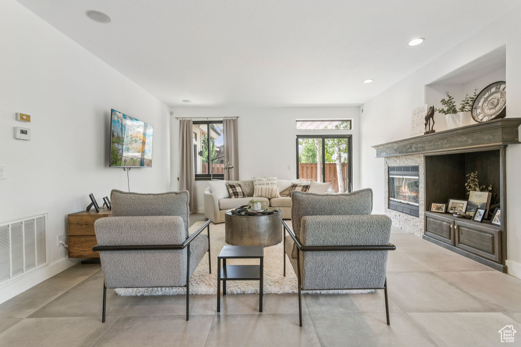 Living room with a glass covered fireplace, recessed lighting, and concrete floors