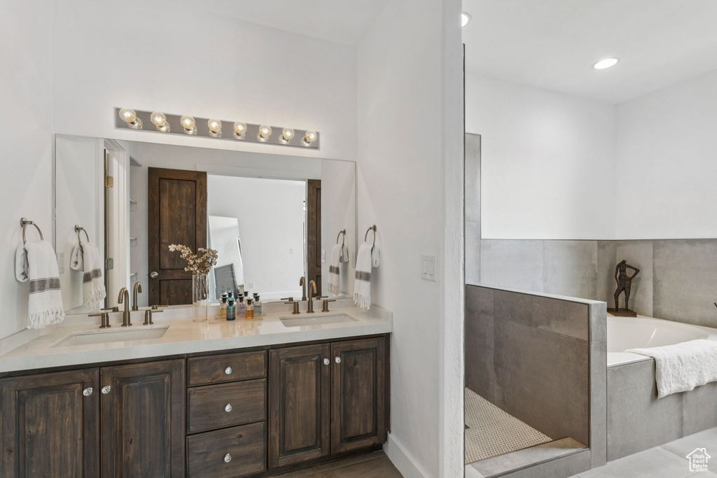 Bathroom featuring double vanity, a garden tub, and walk in shower