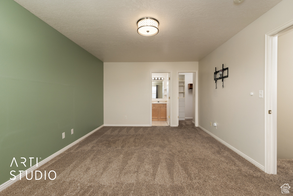 Carpeted spare room featuring baseboards and a textured ceiling