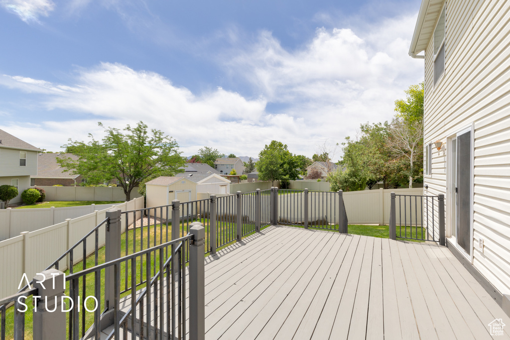 Wooden terrace with a fenced backyard, a storage unit, and a residential view