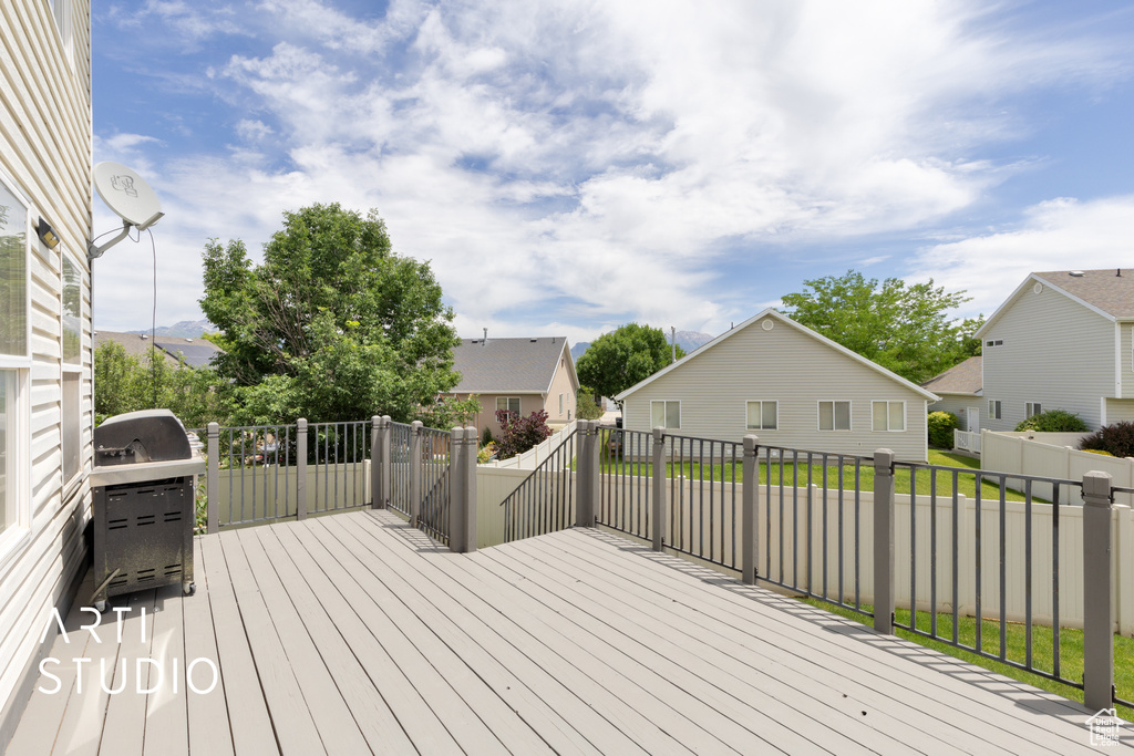 Wooden deck with area for grilling, a residential view, and a fenced backyard