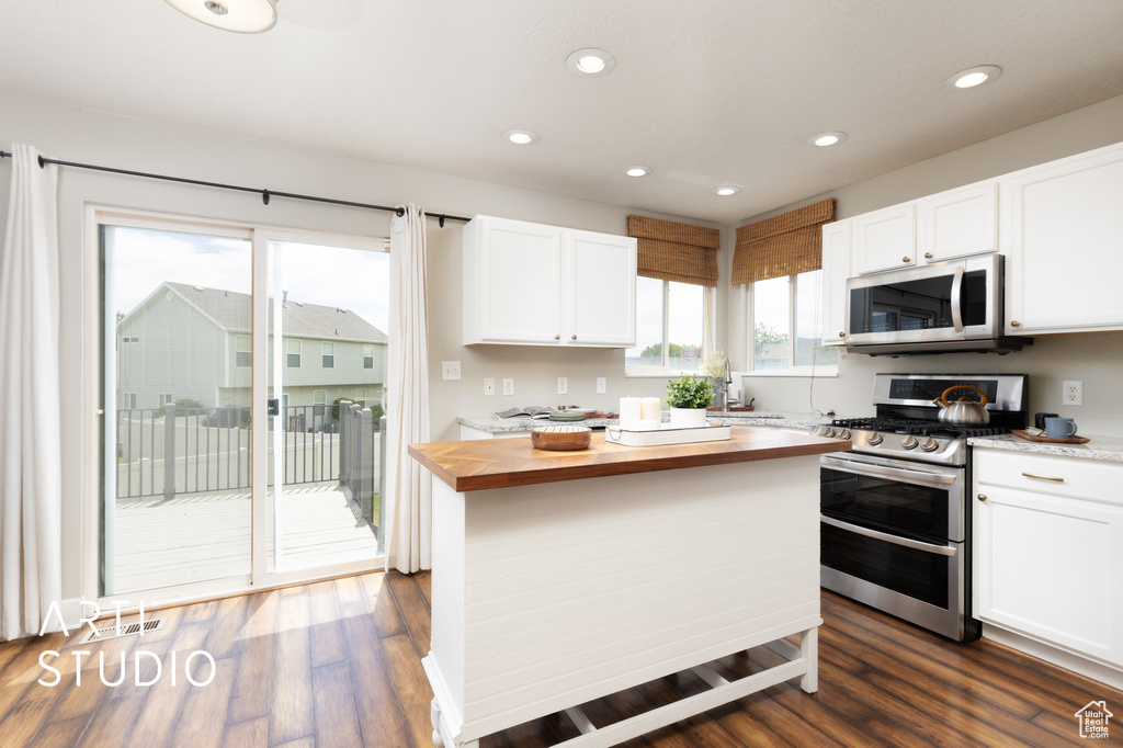 Kitchen featuring appliances with stainless steel finishes, wooden counters, white cabinets, recessed lighting, and dark wood-style floors