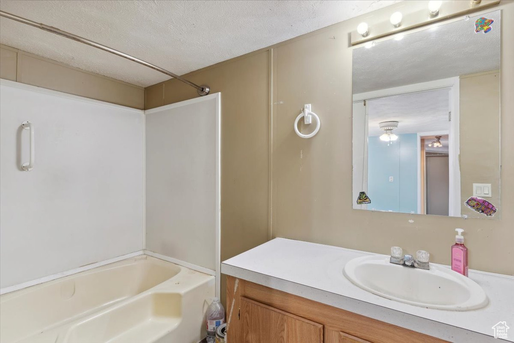 Full bathroom featuring vanity, a textured ceiling, and  shower combination