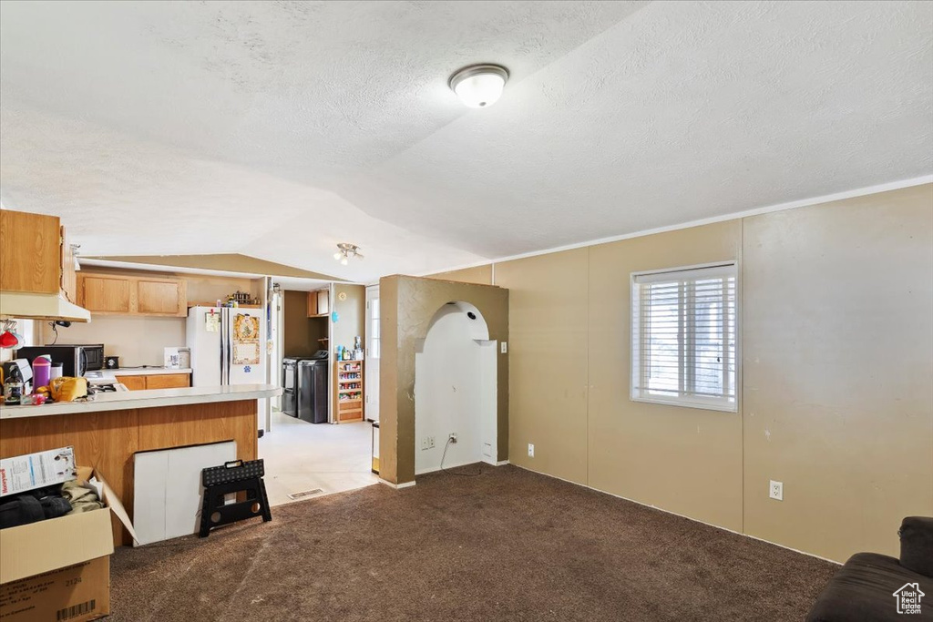 Kitchen with separate washer and dryer, light countertops, freestanding refrigerator, a peninsula, and carpet