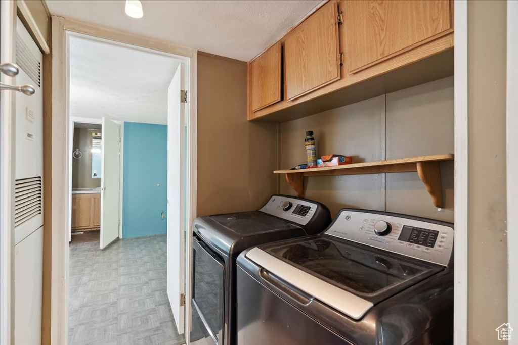 Laundry room featuring washing machine and dryer, cabinet space, and light floors