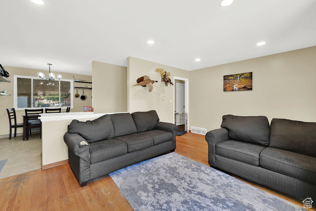 Living room with a chandelier, light wood-style floors, and recessed lighting