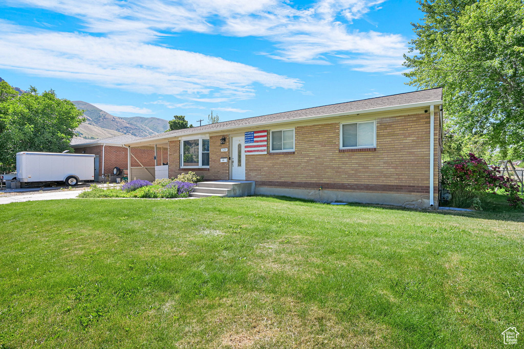 Single story home with brick siding, a front lawn, and a mountain view