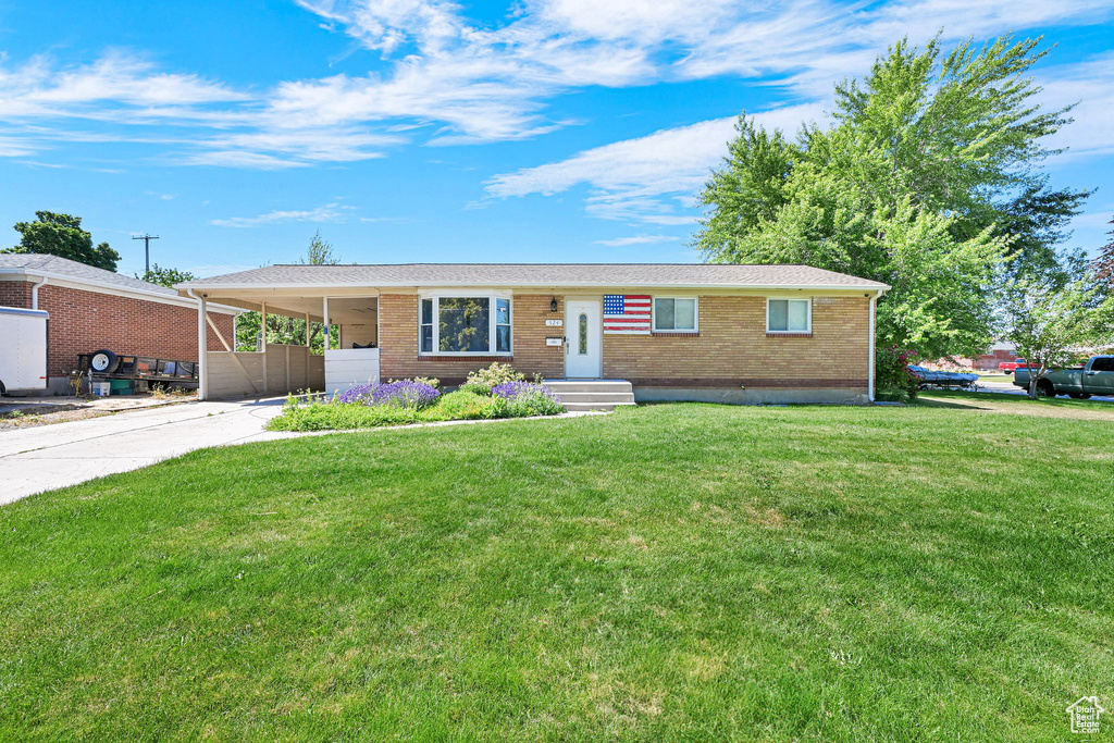 Ranch-style house with brick siding, concrete driveway, a front lawn, and a carport