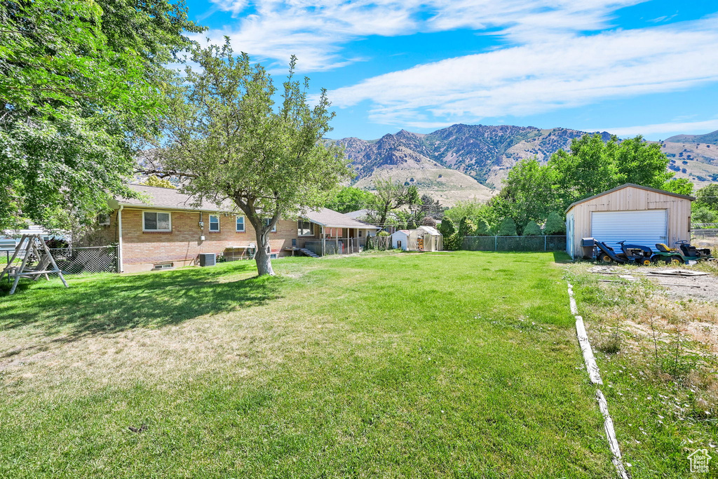 View of yard with a detached garage, a mountain view, an outdoor structure, and dirt driveway