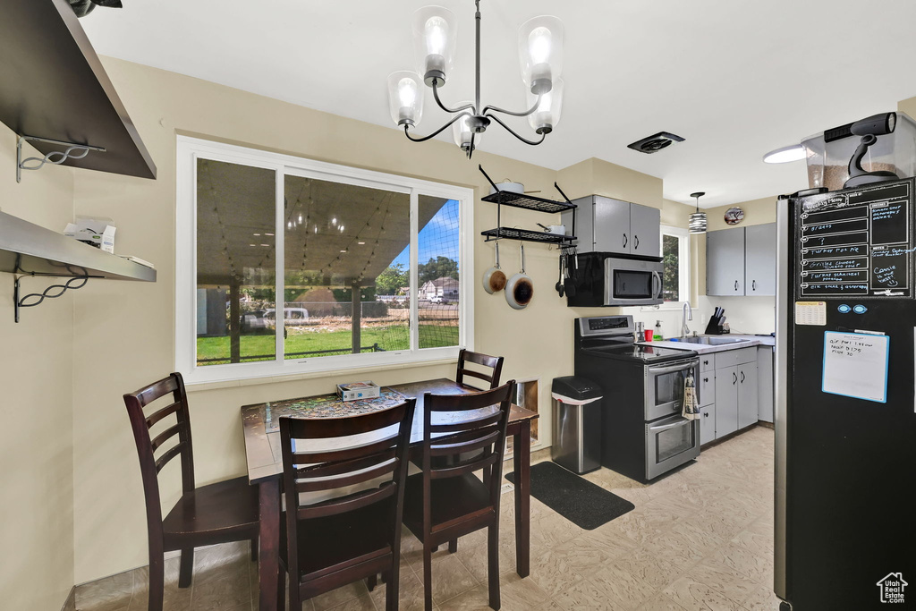 Kitchen with stainless steel appliances, a chandelier, gray cabinetry, hanging light fixtures, and light flooring