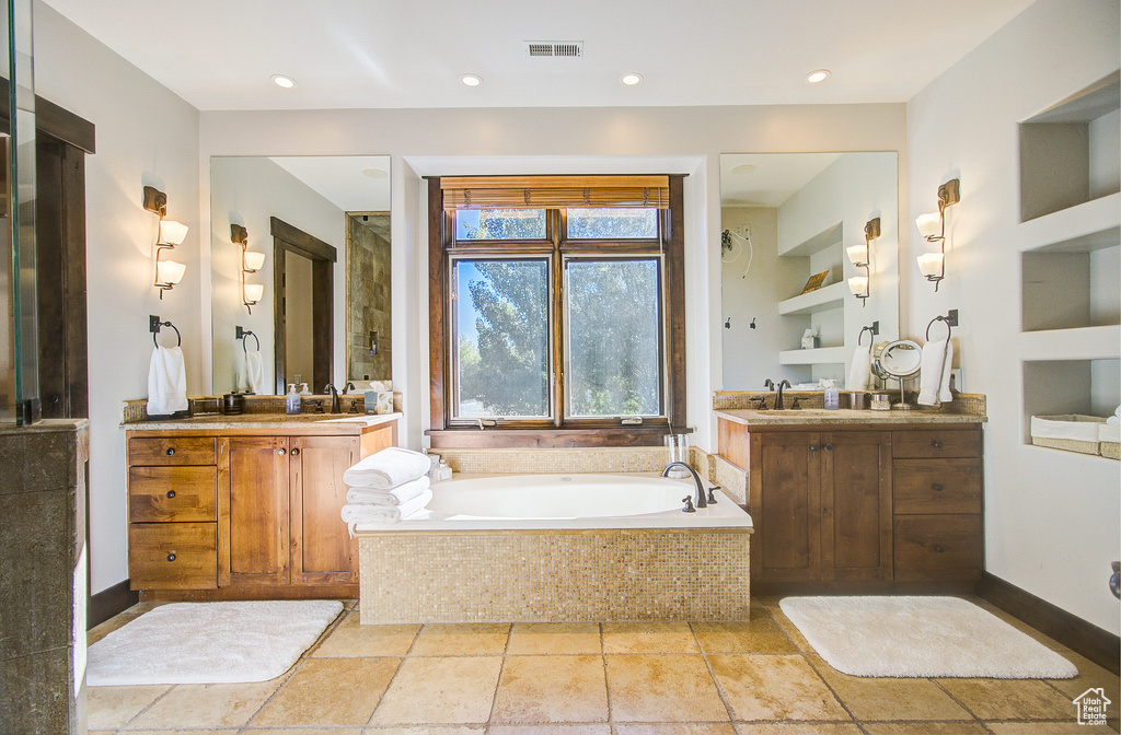 Full bathroom featuring a bath, two vanities, and recessed lighting