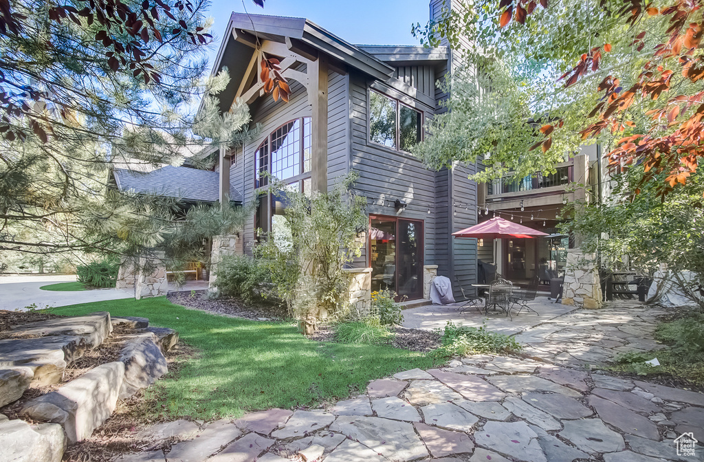 Back of house featuring a patio, a yard, and stone siding