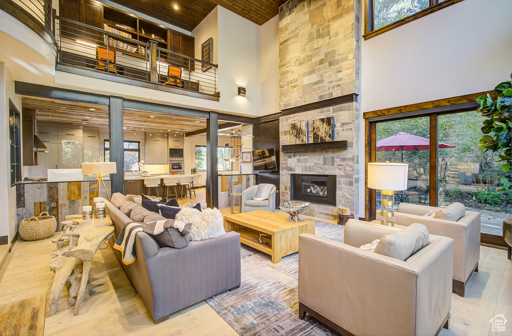 Living area featuring a towering ceiling, a fireplace, wood finished floors, wooden ceiling, and healthy amount of natural light