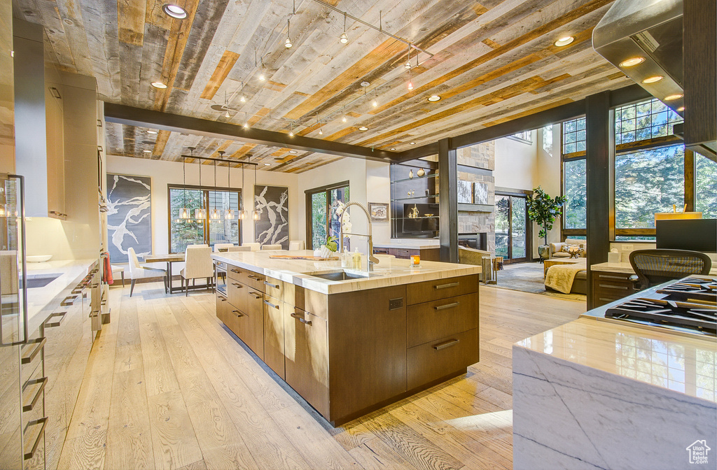 Kitchen with modern cabinets, light wood-style flooring, a large island with sink, open floor plan, and recessed lighting