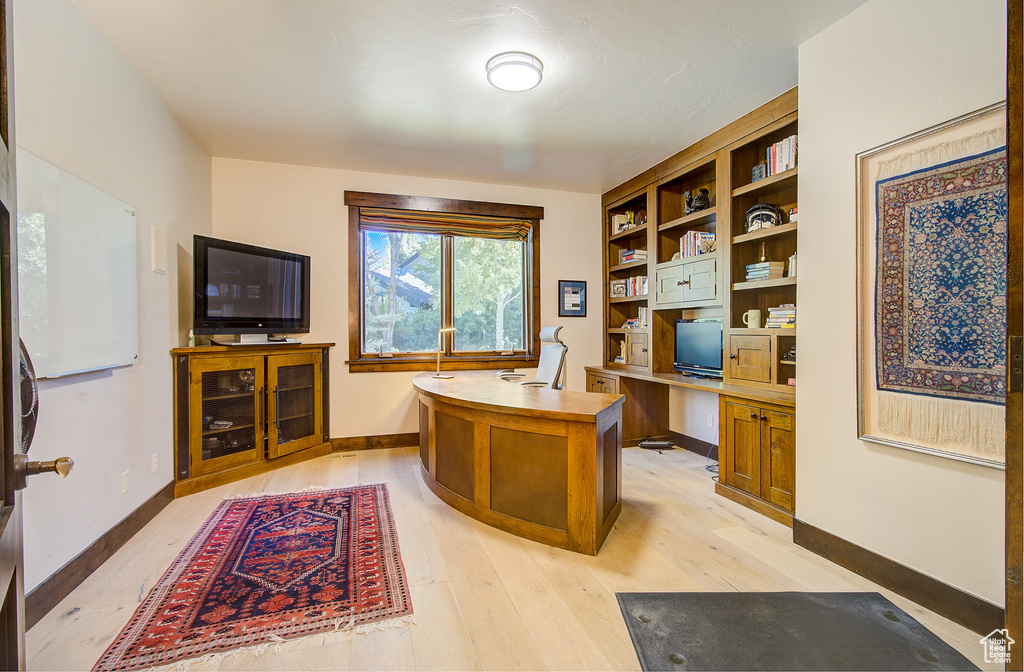 Home office featuring light wood finished floors and built in study area