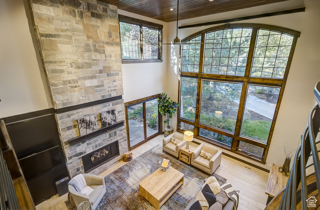 Living room featuring a fireplace, wooden ceiling, wood finished floors, recessed lighting, and a high ceiling