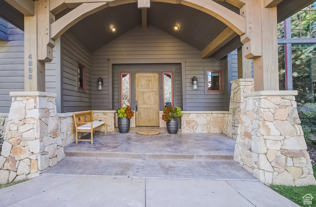 Entrance to property with covered porch and stone siding