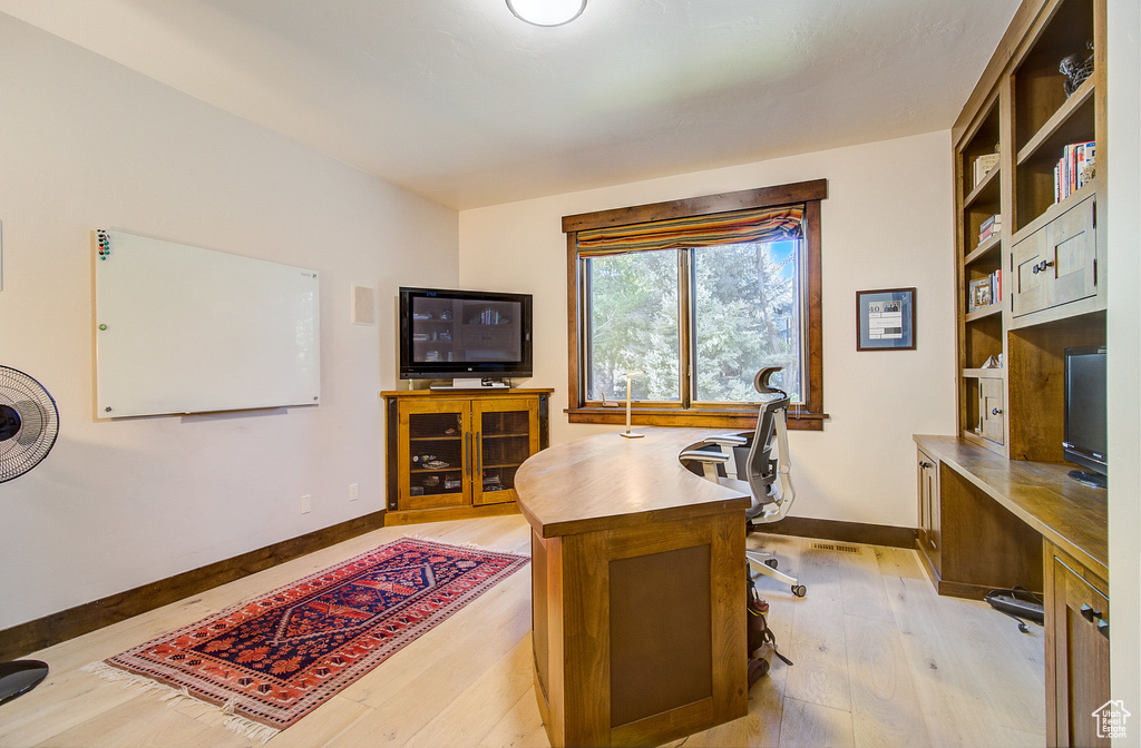 Office area with light wood-type flooring and built in shelves