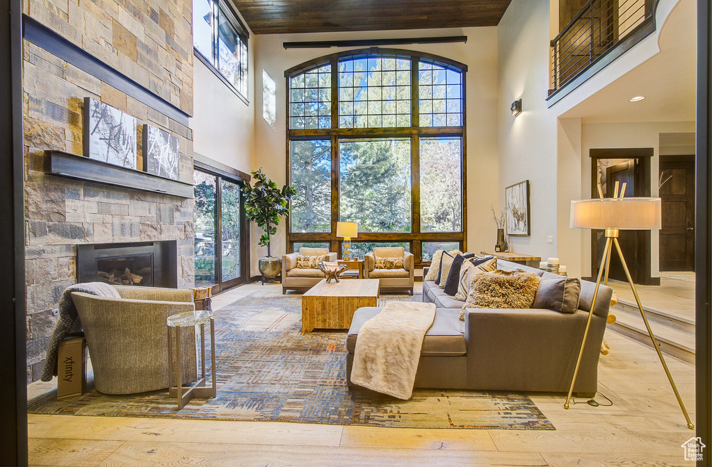 Living room with a towering ceiling, a fireplace, hardwood / wood-style floors, and wooden ceiling