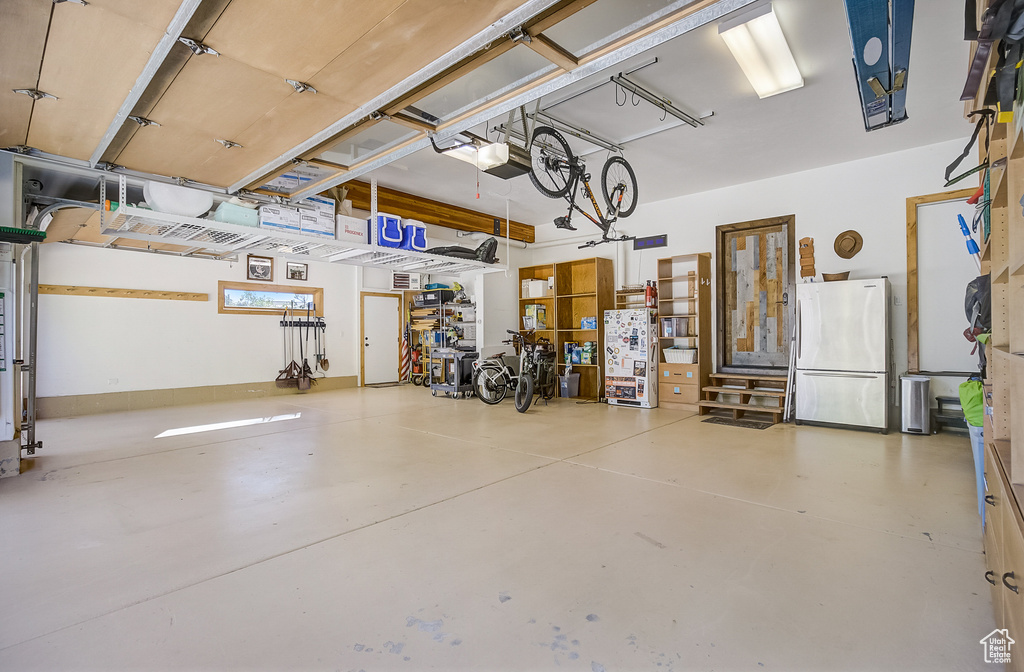 Garage featuring freestanding refrigerator and a garage door opener