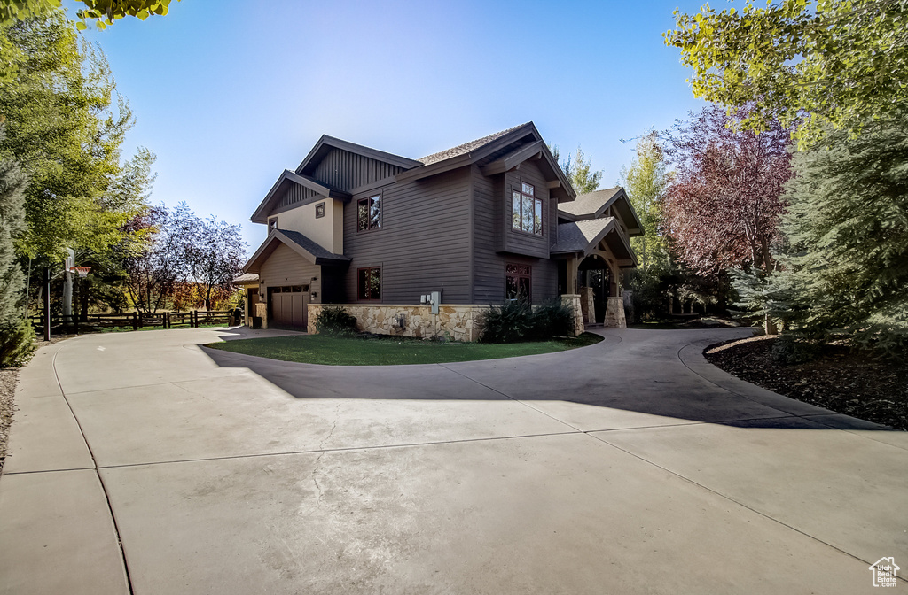 View of side of home with stone siding, curved driveway, and a garage