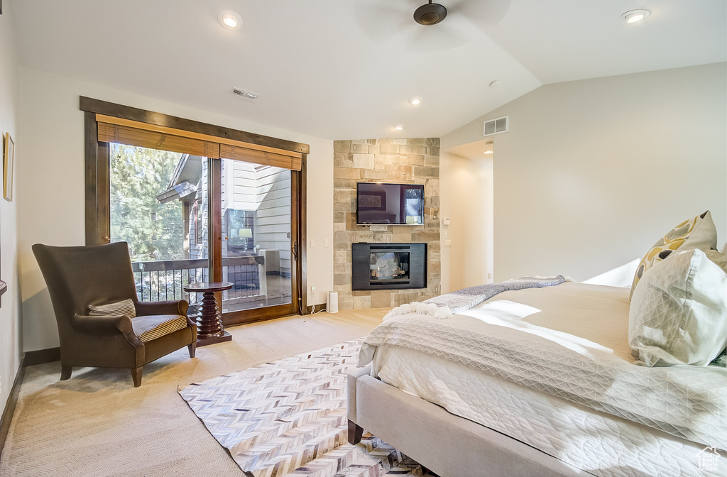 Bedroom featuring a tiled fireplace, vaulted ceiling, recessed lighting, access to exterior, and light carpet