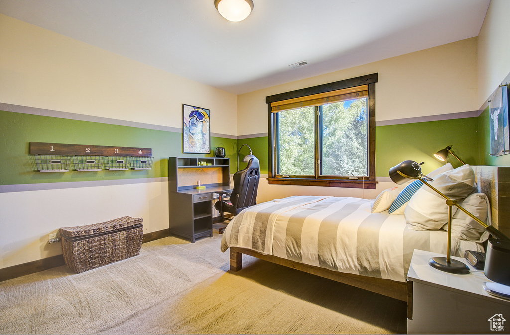 Carpeted bedroom featuring a desk and baseboards