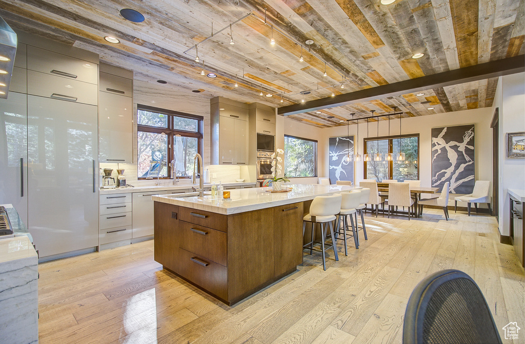 Kitchen featuring modern cabinets, light wood finished floors, a spacious island, light countertops, and hanging light fixtures