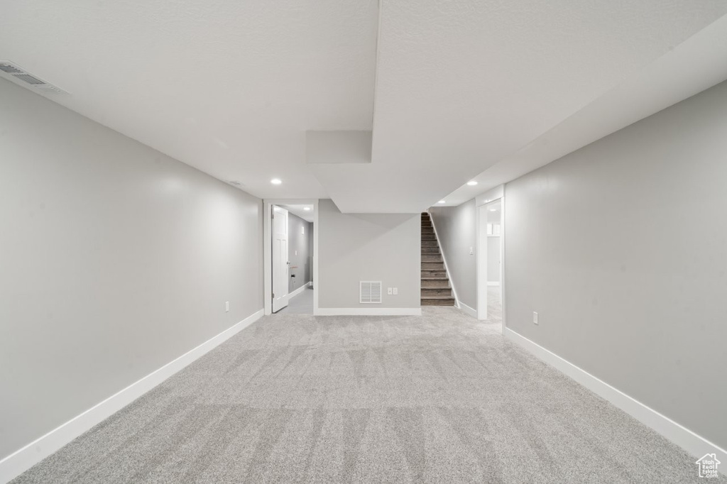 Finished below grade area with recessed lighting, stairs, and carpet