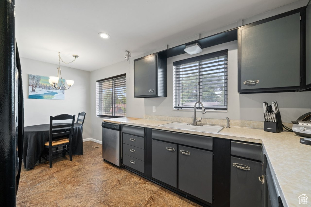 Kitchen featuring stainless steel dishwasher, light countertops, a chandelier, hanging light fixtures, and freestanding refrigerator