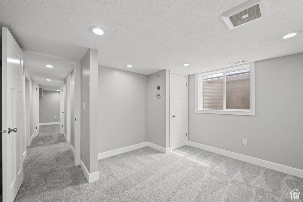 Below grade area featuring carpet floors, a textured ceiling, and recessed lighting