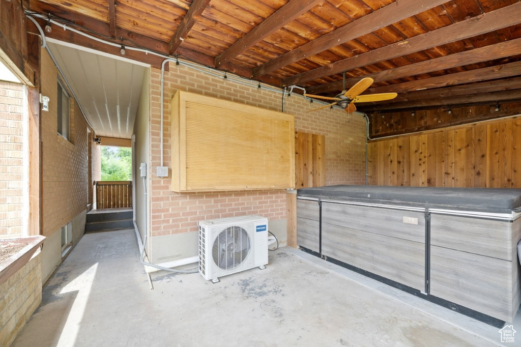 Misc room featuring concrete flooring, brick wall, ceiling fan, and beamed ceiling