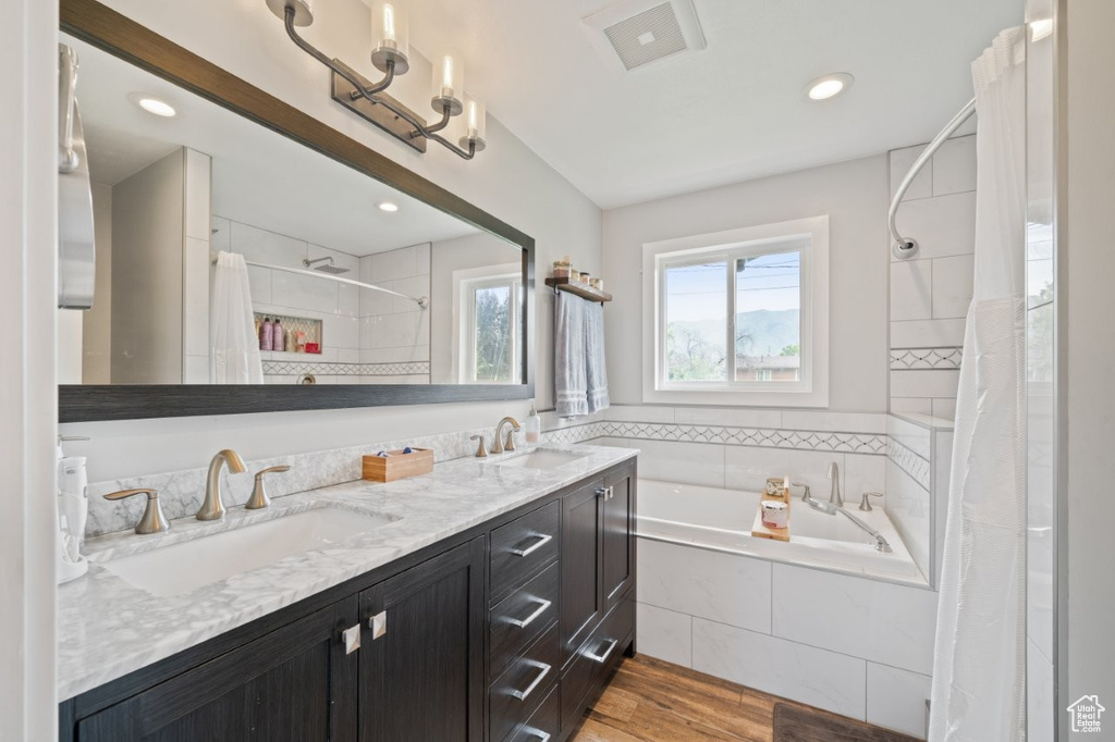 Full bath with a bath, a tile shower, wood finished floors, double vanity, and recessed lighting