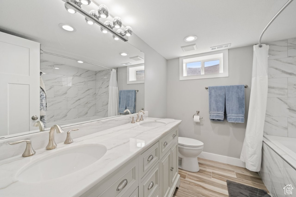 Full bath featuring double vanity, recessed lighting, shower / tub combo with curtain, and wood finished floors