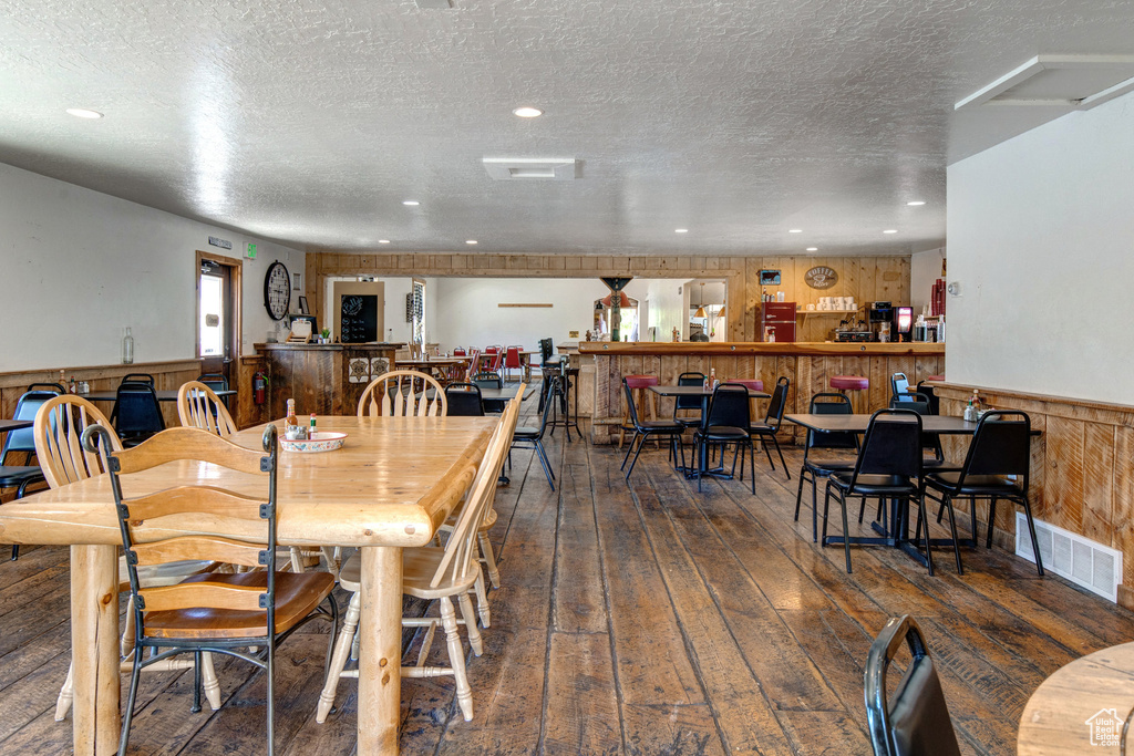 Dining area featuring hardwood / wood-style flooring, wainscoting, a textured ceiling, recessed lighting, and wooden walls