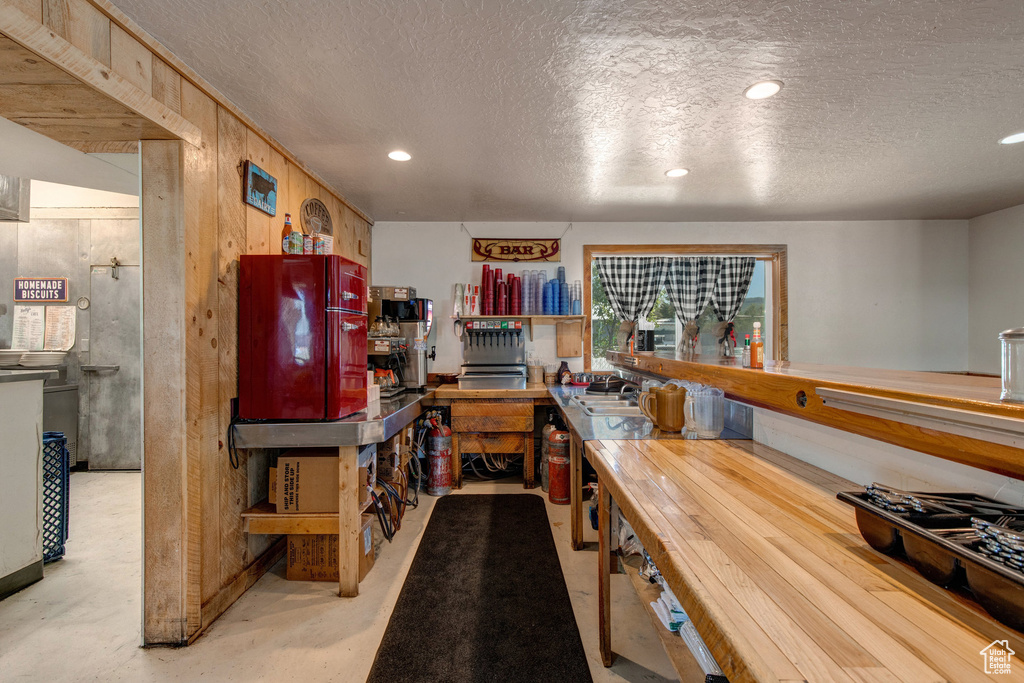 Kitchen featuring a textured ceiling, concrete floors, recessed lighting, and wooden walls