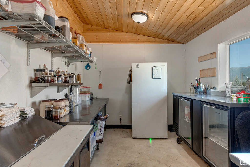 Kitchen with freestanding refrigerator, vaulted ceiling, open shelves, concrete flooring, and wood ceiling