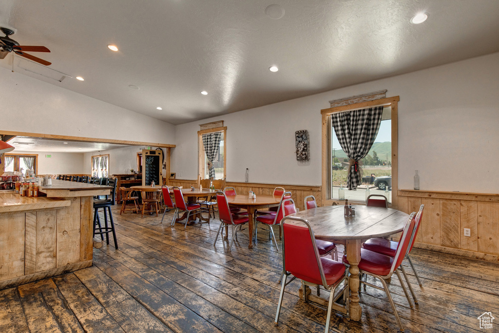 Dining room featuring wainscoting, hardwood / wood-style floors, recessed lighting, wooden walls, and lofted ceiling
