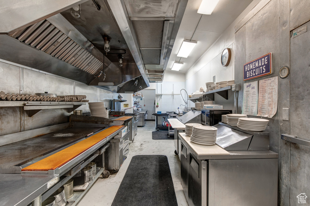 Kitchen with unfinished concrete flooring and ventilation hood