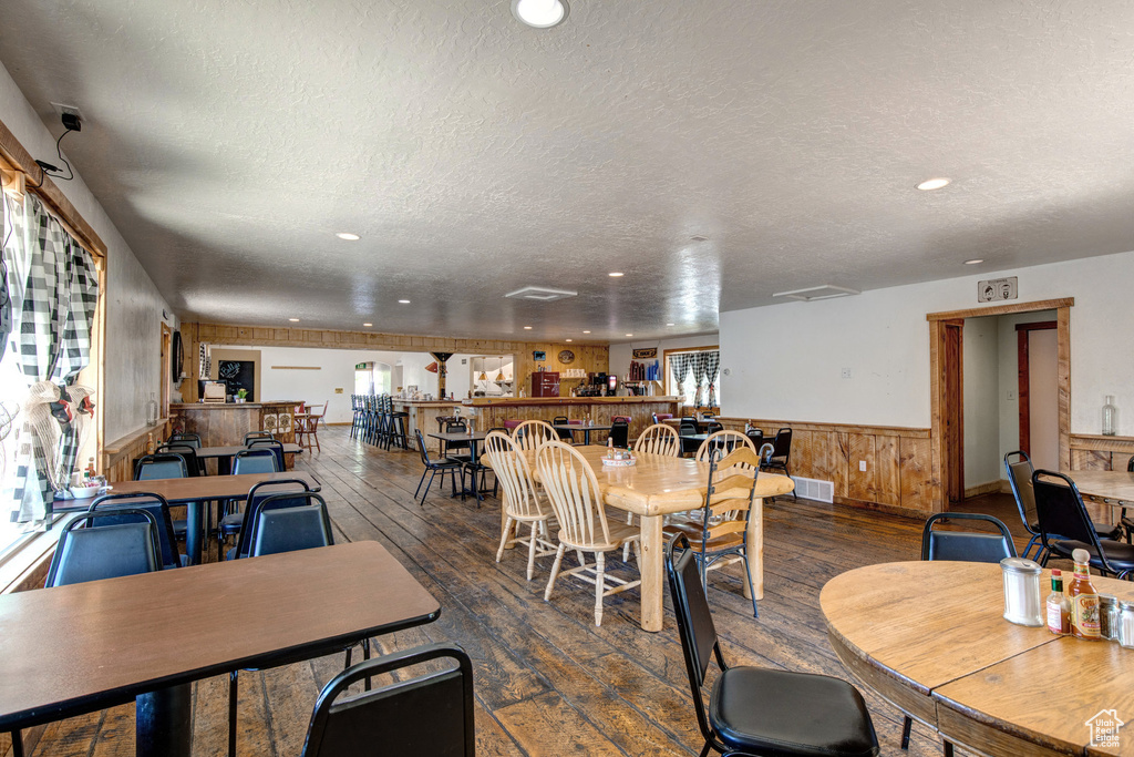 Dining room featuring wood-type flooring, wainscoting, a textured ceiling, recessed lighting, and healthy amount of natural light