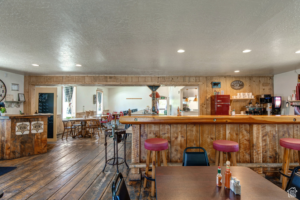 Indoor dry bar featuring wood-type flooring, wooden walls, recessed lighting, and a textured ceiling