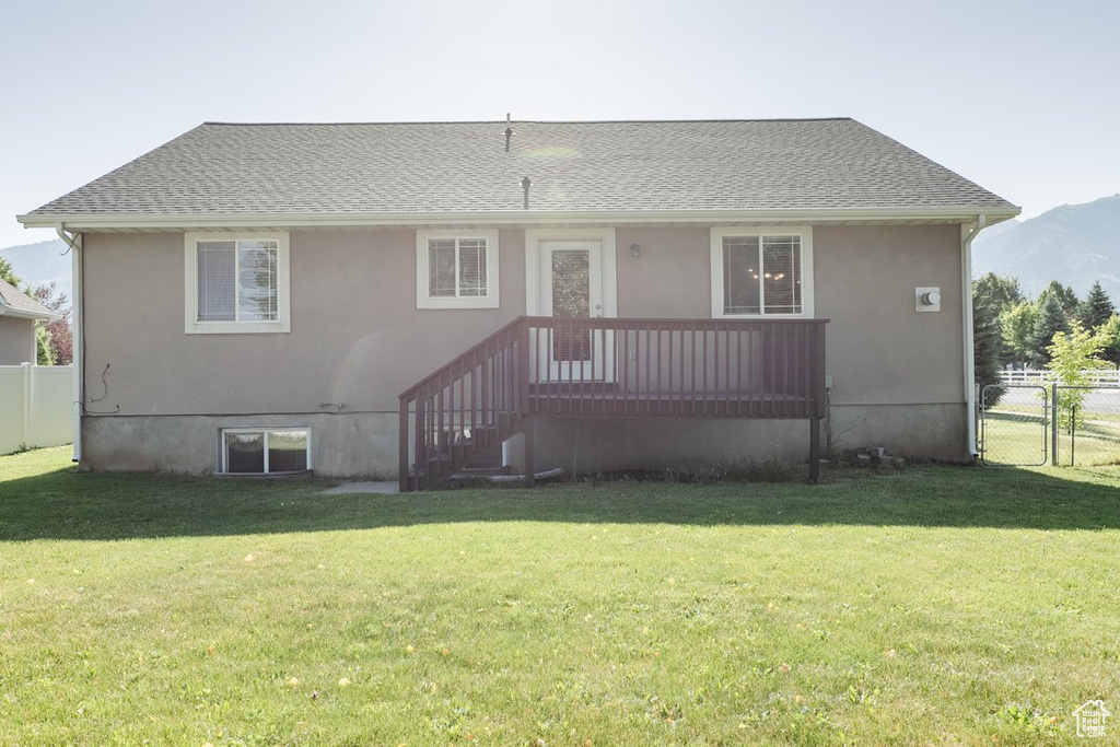Rear view of house with stucco siding, a shingled roof, and a mountain view