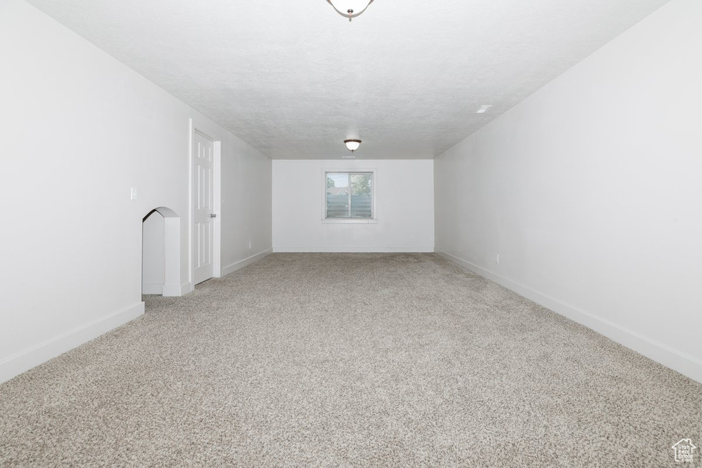 Unfurnished room featuring light carpet and baseboards