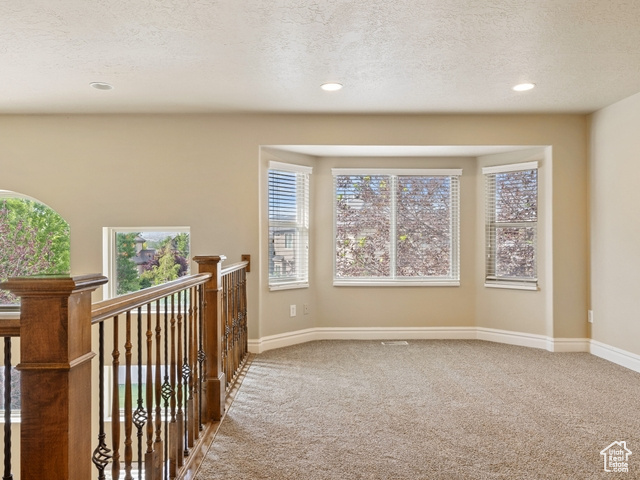 Hall featuring carpet, healthy amount of natural light, recessed lighting, a textured ceiling, and an upstairs landing