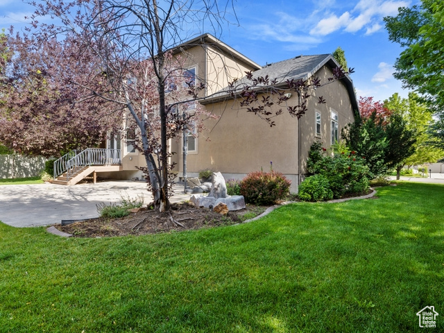 View of property exterior featuring a lawn, stucco siding, and a patio