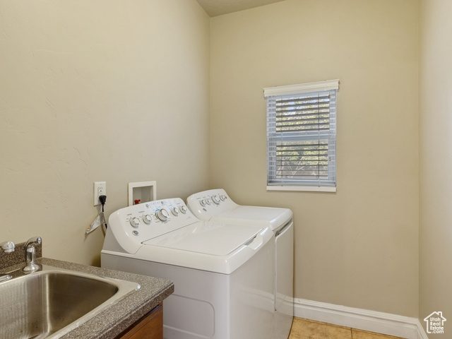 Washroom with washing machine and clothes dryer and light tile patterned floors