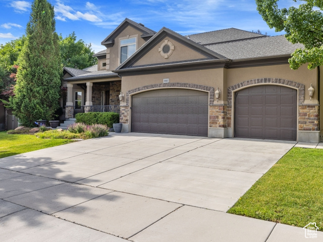 View of front of property featuring stucco siding, stone siding, an attached garage, and concrete driveway