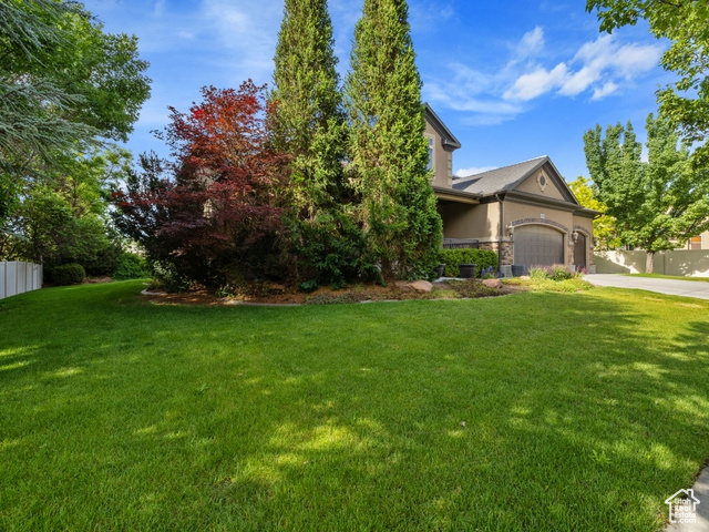 Obstructed view of property featuring concrete driveway, a garage, stucco siding, and stone siding