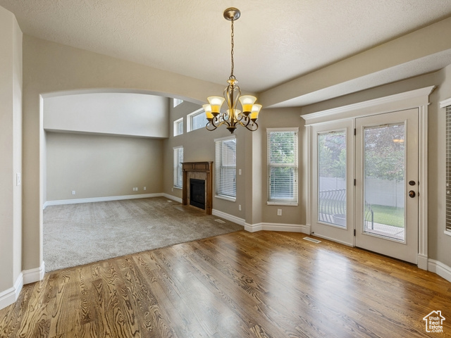 Unfurnished living room featuring wood finished floors, a chandelier, a fireplace, and arched walkways