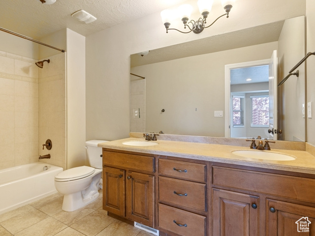 Full bathroom featuring double vanity, tile patterned floors, washtub / shower combination, and a textured ceiling